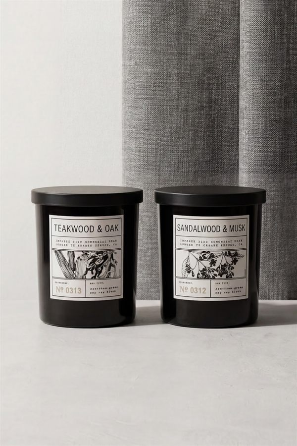 Two black candle jars with hand-drawn botanical labels